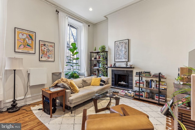 living room with light wood-type flooring, ornamental molding, and a fireplace