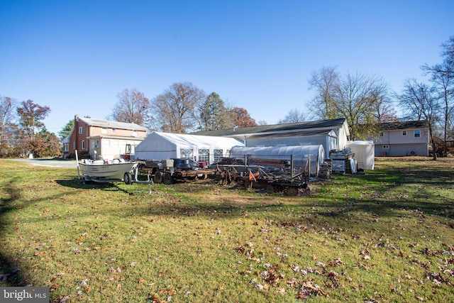 back of property with a lawn and an outdoor structure