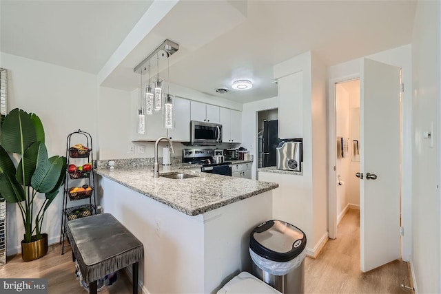 kitchen with kitchen peninsula, stainless steel appliances, sink, pendant lighting, and white cabinets