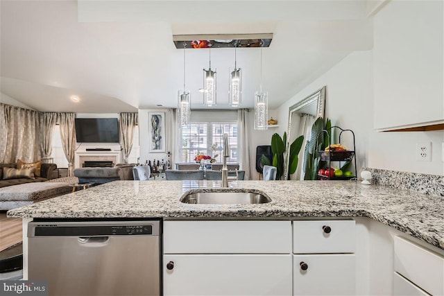 kitchen with kitchen peninsula, light stone countertops, stainless steel dishwasher, sink, and white cabinets