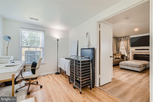 office space with a fireplace and light hardwood / wood-style flooring