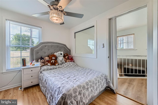 bedroom with multiple windows, light wood-type flooring, a closet, and ceiling fan