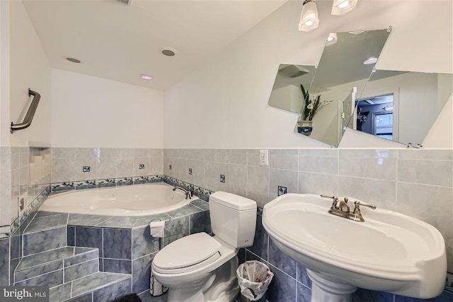 bathroom with a relaxing tiled tub, toilet, and sink