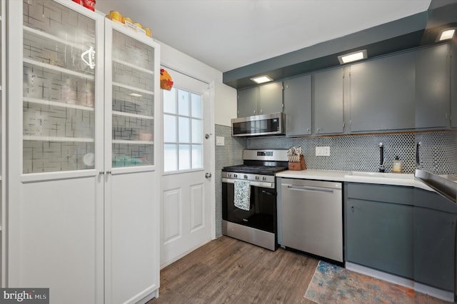 kitchen with gray cabinetry, backsplash, sink, dark hardwood / wood-style floors, and appliances with stainless steel finishes