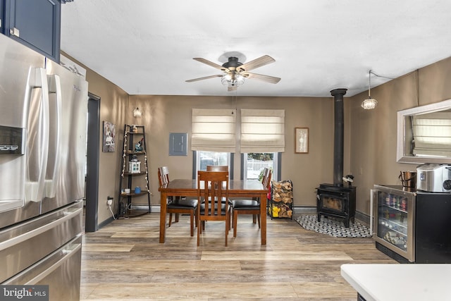 dining room featuring a wood stove, a baseboard radiator, light wood-style flooring, and a ceiling fan