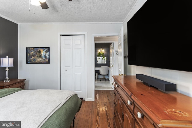 bedroom with a closet, dark wood-style flooring, ornamental molding, and a textured ceiling