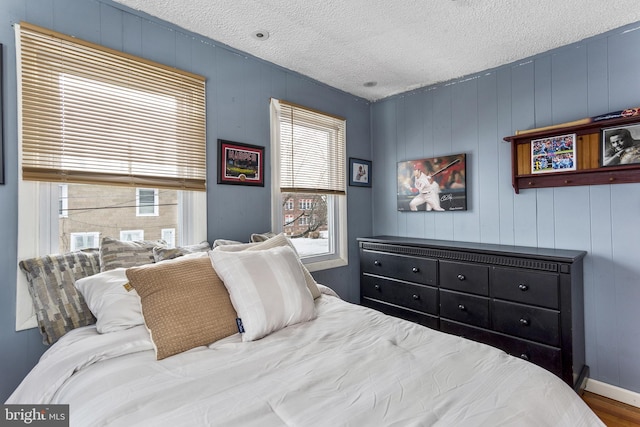 bedroom with a textured ceiling, wood finished floors, and baseboards