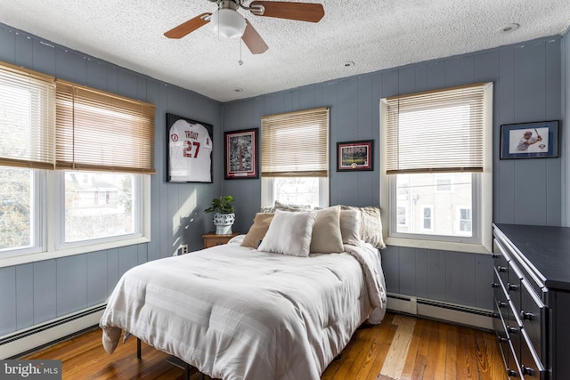 bedroom with dark wood-type flooring, multiple windows, and a baseboard radiator