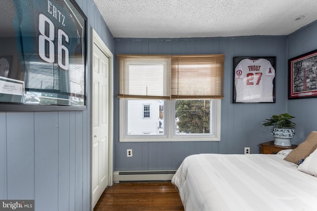 bedroom with dark wood-style floors, a textured ceiling, and baseboard heating