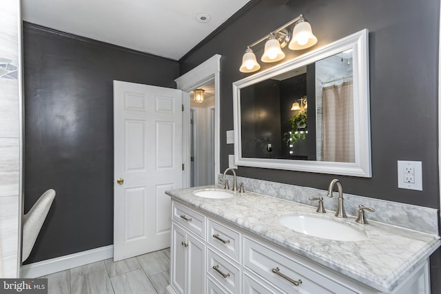 bathroom featuring double vanity, a sink, and baseboards