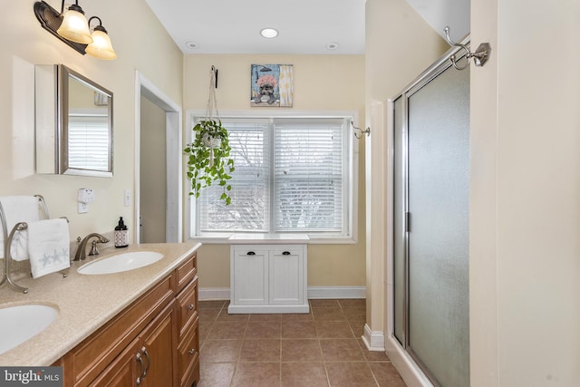 full bathroom with double vanity, a sink, a shower stall, and tile patterned floors