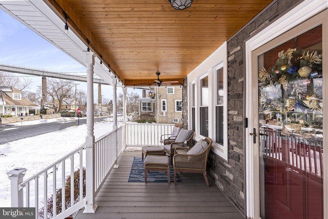 snow covered deck featuring a residential view, a porch, and a ceiling fan