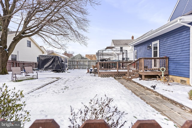 snowy yard with a gazebo, a trampoline, fence, and a wooden deck