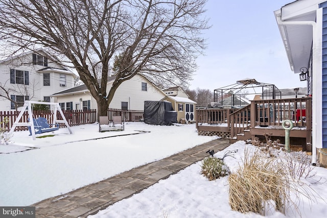 snowy yard with fence, a wooden deck, and a gazebo