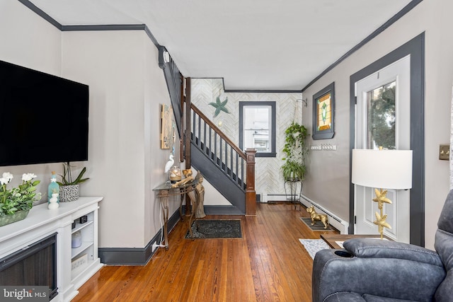 entryway with a baseboard radiator, wood finished floors, baseboards, stairs, and crown molding