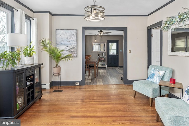 sitting room with visible vents, ornamental molding, wood finished floors, a chandelier, and baseboards