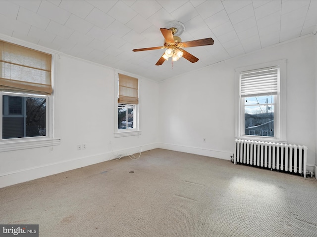 carpeted spare room featuring crown molding, ceiling fan, and radiator