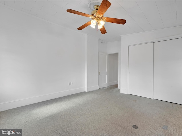 unfurnished bedroom featuring ceiling fan, ornamental molding, carpet flooring, and a closet