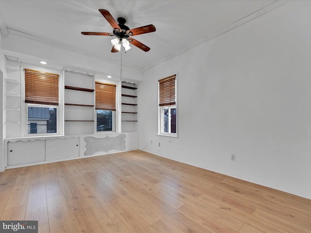 unfurnished living room with ceiling fan, light wood-type flooring, and built in shelves