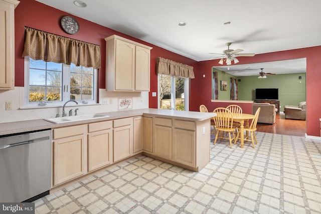 kitchen with a sink, a peninsula, dishwasher, and light brown cabinetry