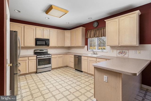 kitchen featuring a sink, a peninsula, appliances with stainless steel finishes, and light brown cabinets