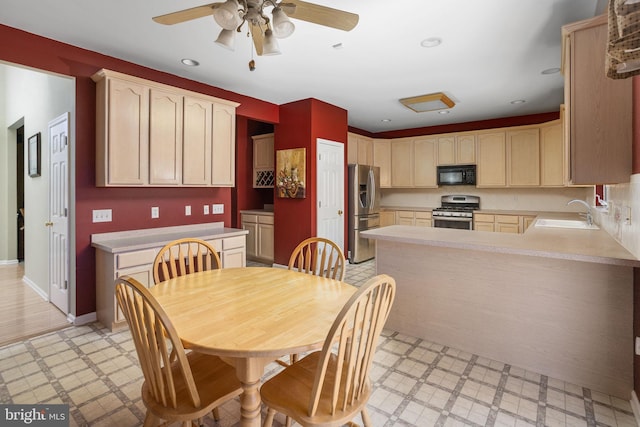 kitchen with stainless steel appliances, a peninsula, a sink, light countertops, and light floors