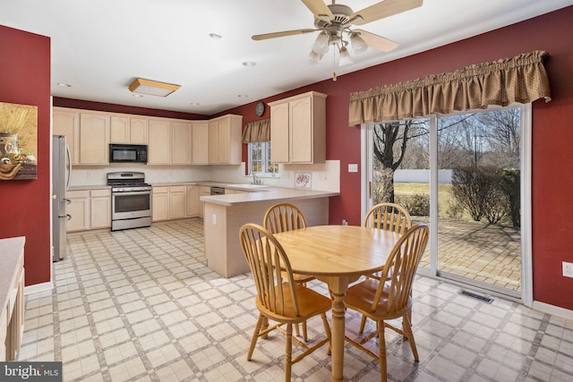 kitchen featuring light floors, visible vents, appliances with stainless steel finishes, a sink, and a peninsula