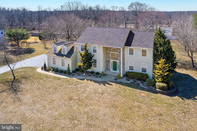 view of front of house featuring a shingled roof and a front yard