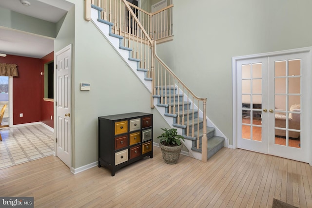 stairs with french doors, hardwood / wood-style floors, and a high ceiling