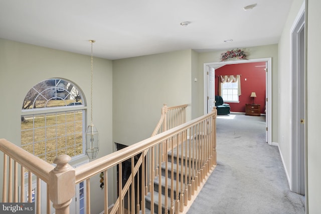 hall with carpet flooring, an upstairs landing, and baseboards