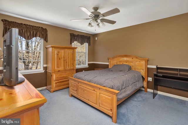 bedroom featuring light carpet, multiple windows, baseboards, and a ceiling fan