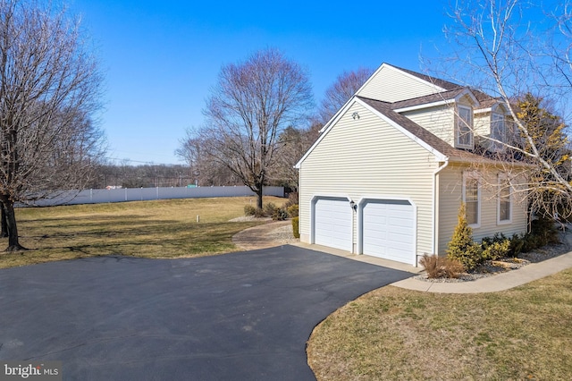 view of property exterior with aphalt driveway, a garage, fence, a yard, and roof with shingles