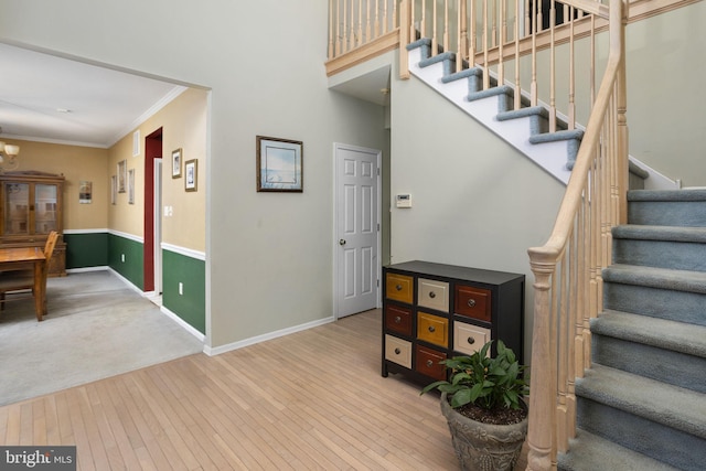 stairs featuring an inviting chandelier, baseboards, ornamental molding, and hardwood / wood-style floors