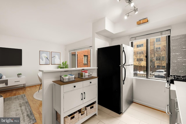 kitchen featuring a healthy amount of sunlight, white cabinetry, light wood-type flooring, and stainless steel appliances