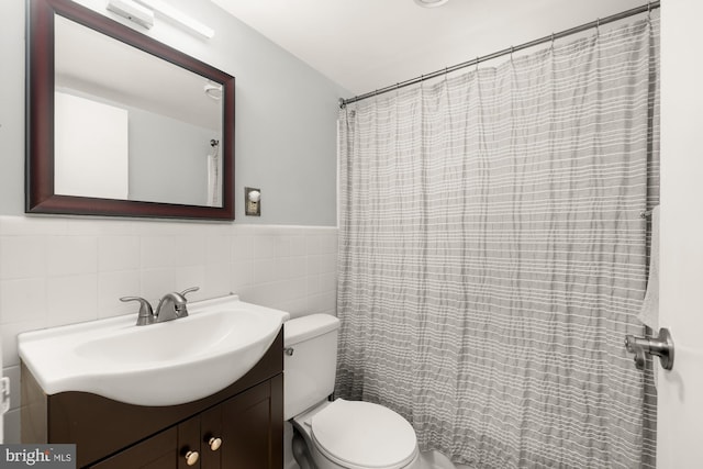 bathroom with toilet, vanity, and tile walls