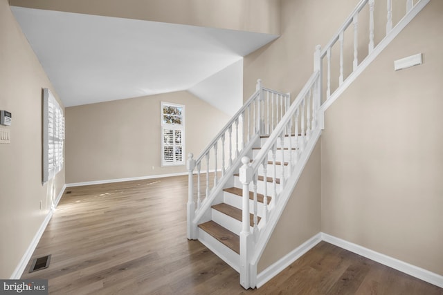 stairway with lofted ceiling and wood-type flooring