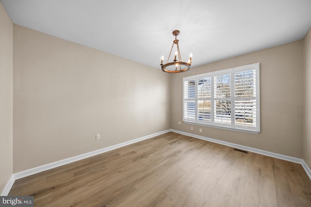 unfurnished room featuring light wood-type flooring and a notable chandelier