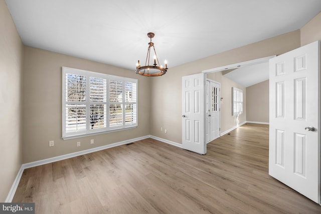 unfurnished dining area with an inviting chandelier and light hardwood / wood-style floors