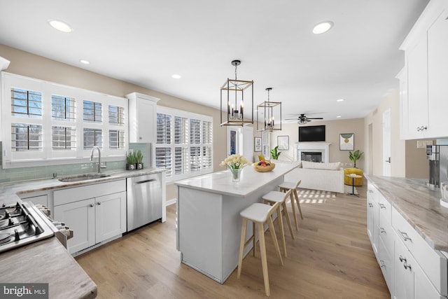 kitchen with a center island, plenty of natural light, sink, white cabinetry, and stainless steel dishwasher