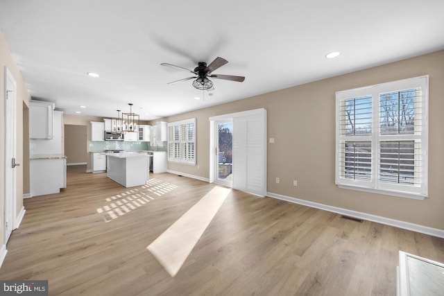 unfurnished living room featuring light hardwood / wood-style floors and ceiling fan with notable chandelier