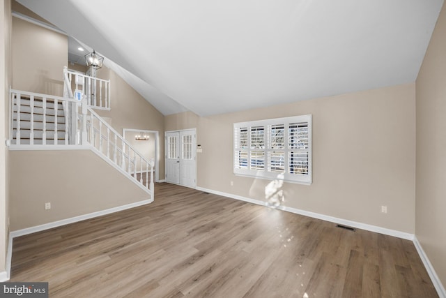 unfurnished living room featuring lofted ceiling, a chandelier, and wood-type flooring