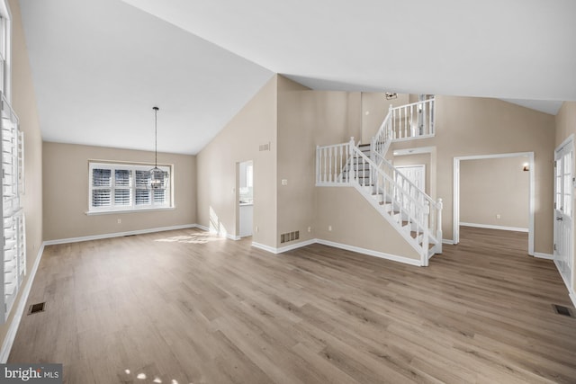 unfurnished living room with a notable chandelier, high vaulted ceiling, and wood-type flooring