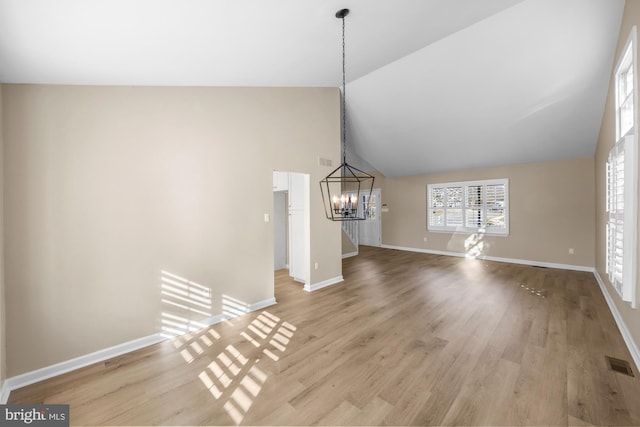 unfurnished living room with lofted ceiling, a notable chandelier, and light hardwood / wood-style flooring