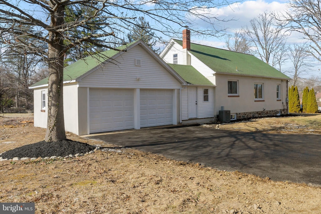 view of property exterior featuring cooling unit and a garage