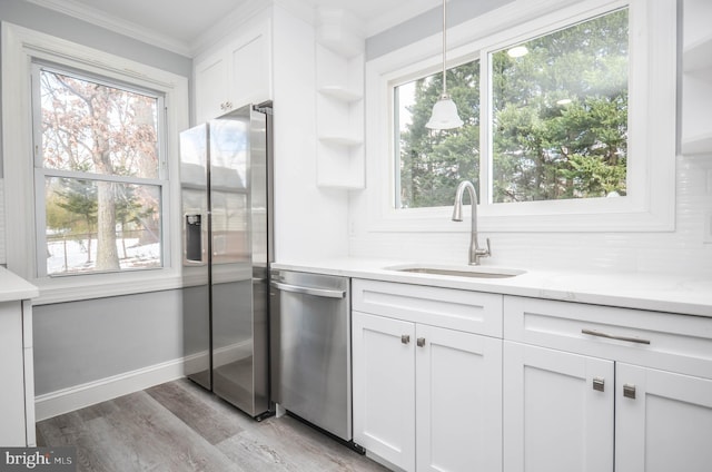 kitchen with light stone countertops, white cabinetry, sink, stainless steel appliances, and light wood-type flooring