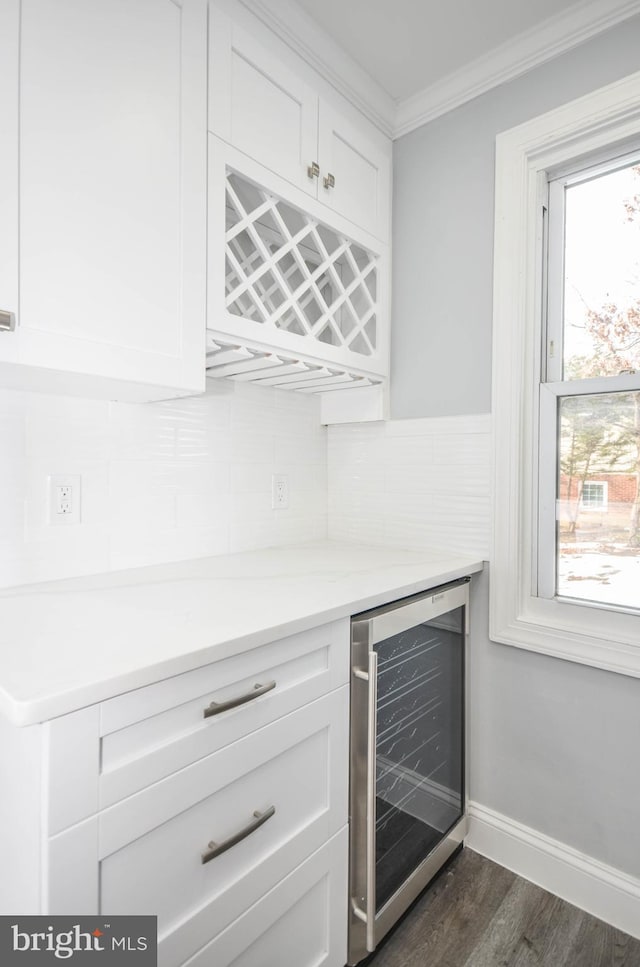 bar featuring wine cooler, ornamental molding, dark wood-type flooring, white cabinetry, and plenty of natural light