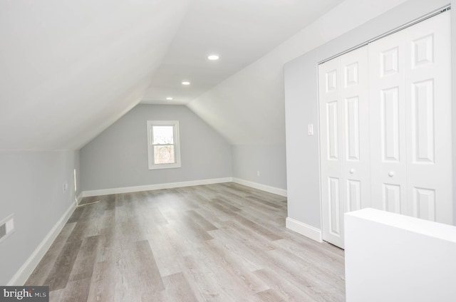 additional living space with light hardwood / wood-style floors and lofted ceiling