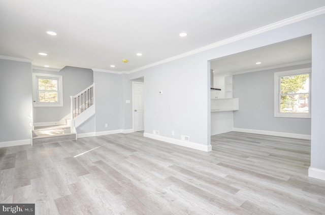 unfurnished living room featuring plenty of natural light, light hardwood / wood-style flooring, and ornamental molding