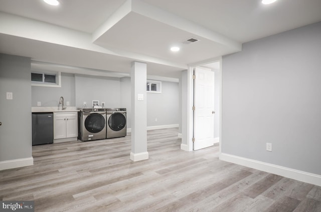 laundry area with cabinets, independent washer and dryer, sink, and light hardwood / wood-style flooring