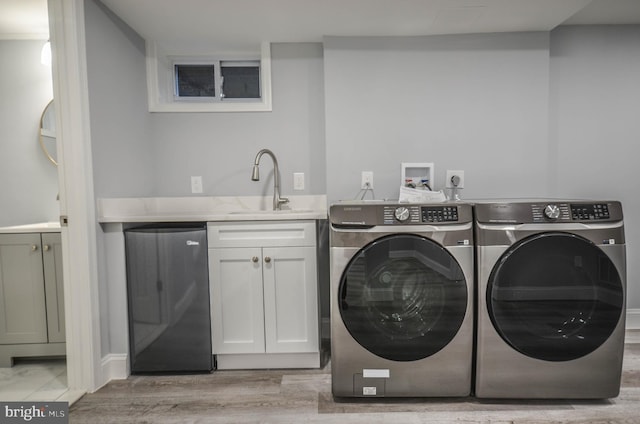 washroom with cabinets, washing machine and dryer, light hardwood / wood-style floors, and sink